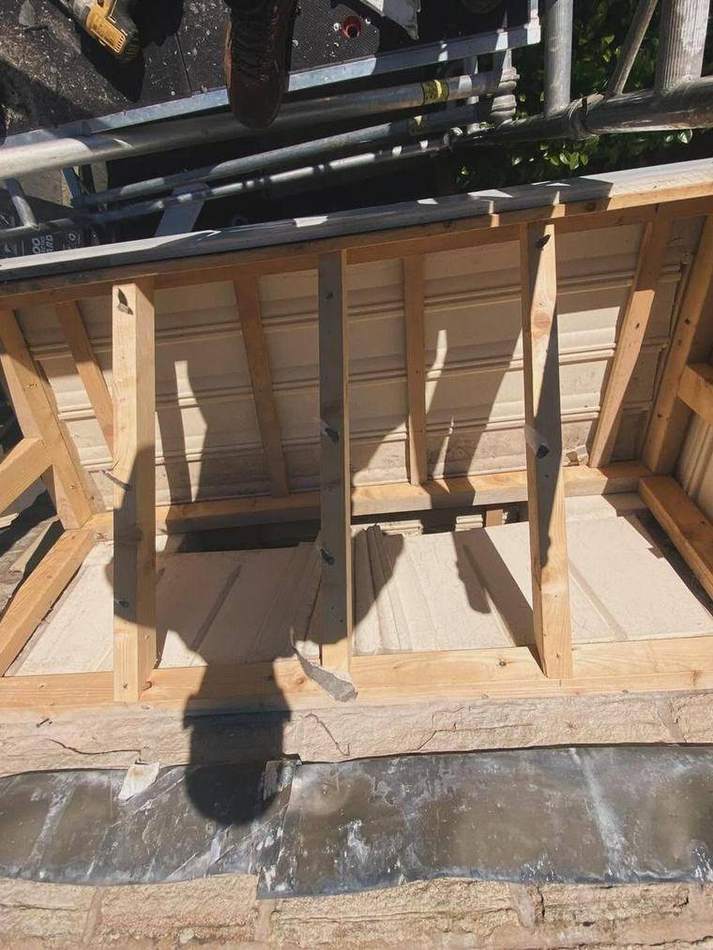 New timber canopy carcass built up over the doorway, seen from the scaffold above