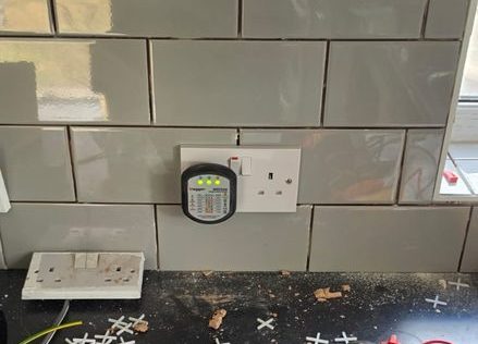 Test meter and faceplates laid out on a worktop during electrical testing and certification