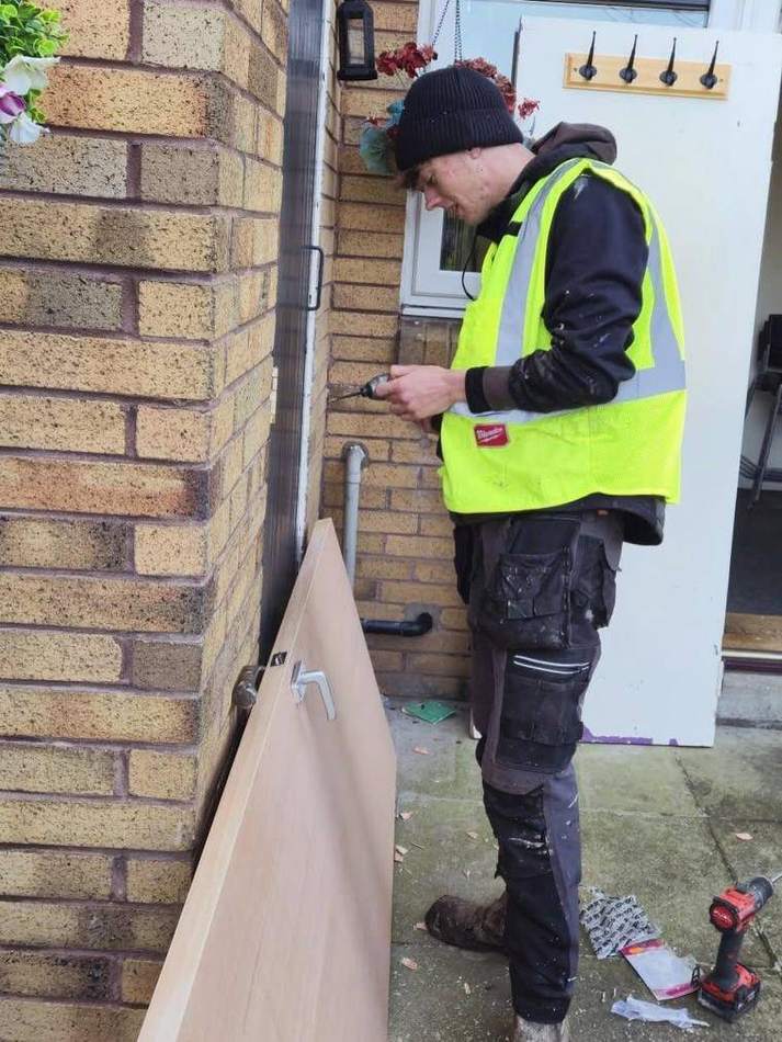 Joiner preparing a new internal door outside a property before hanging it