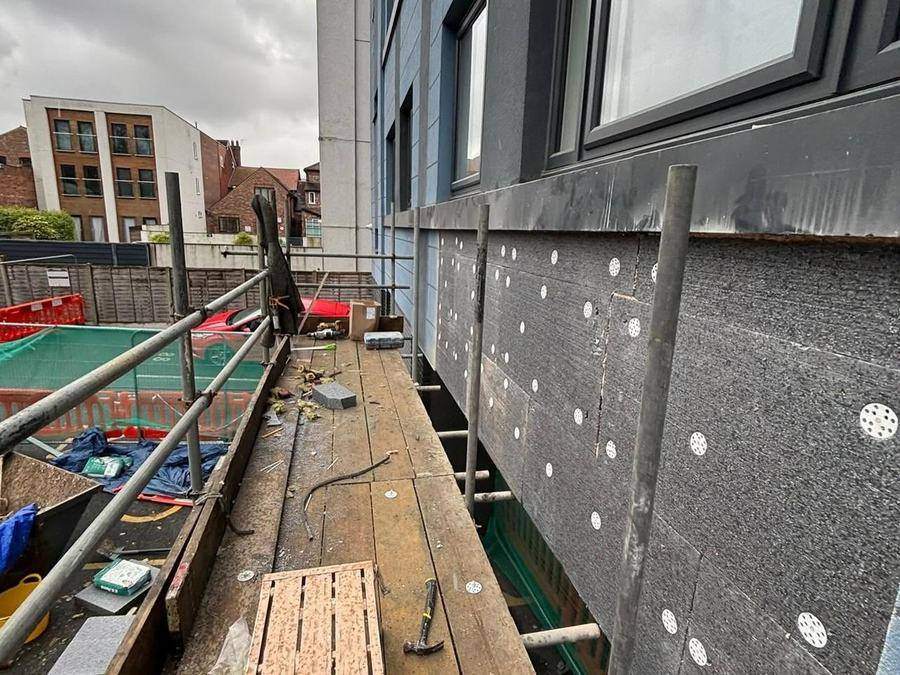New black breather membrane fixed across the opened-up external wall with insulation washers at regular centres
