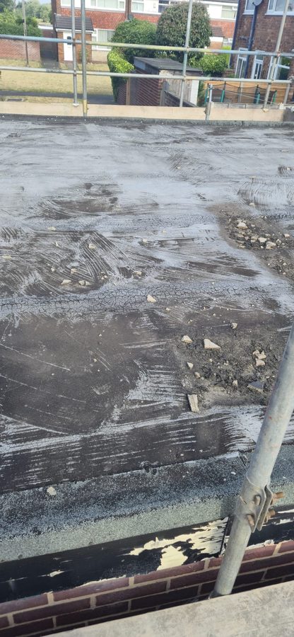 Worn and patched flat roof covering before it is stripped