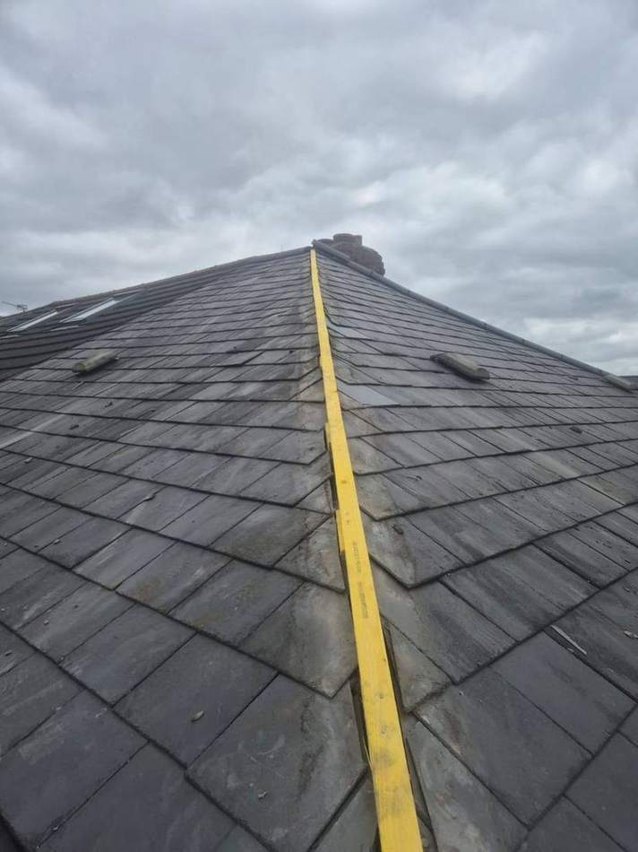 Slate roof hip with the old mortar-bedded hip tiles stripped off and a dry-fix hip batten fixed along the hip line, ready for the new hip tiles to be mechanically fixed