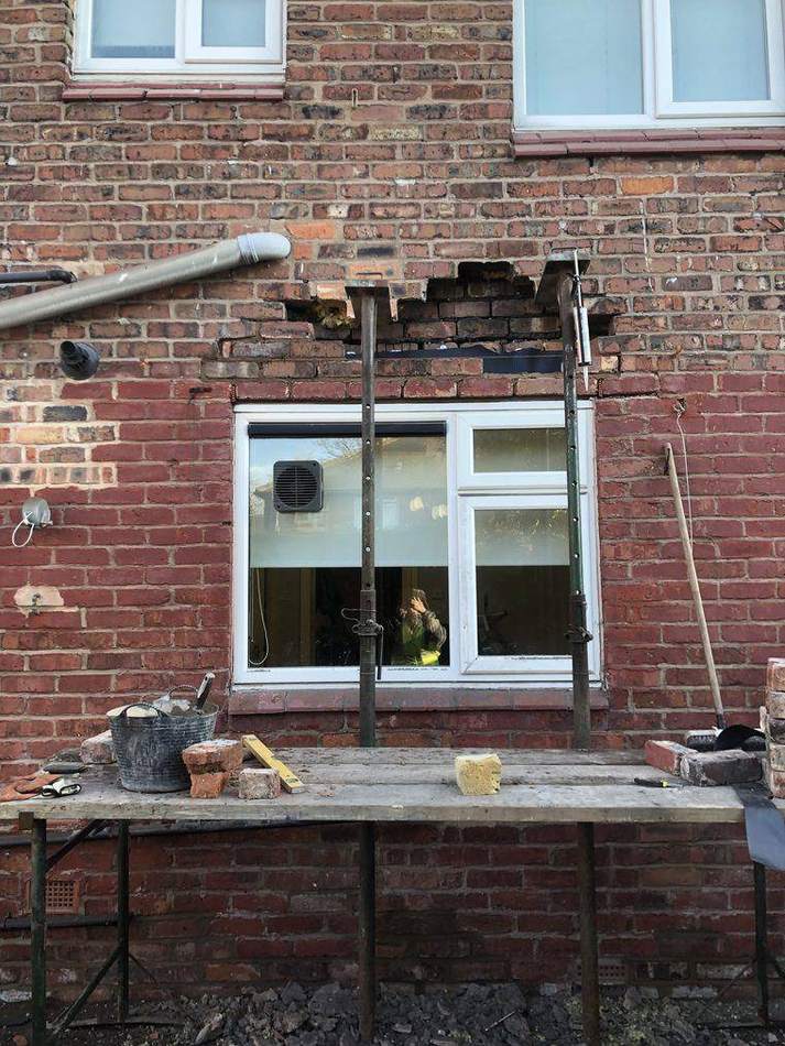 Brickwork removed above a window opening with acrow props supporting the wall during lintel replacement