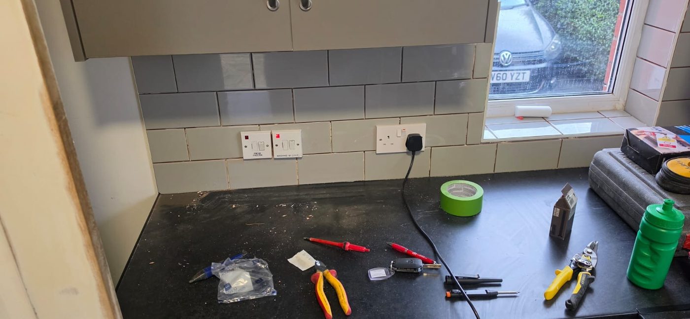 Kitchen worktop during second fix, with test meter, hand tools and faceplates laid out