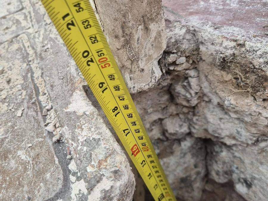 Tape measure run down into the void beneath the paving to record its depth before backfilling