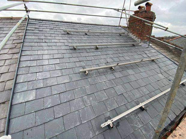 Completed natural slate roof with safety rail system fitted, viewed from the scaffold