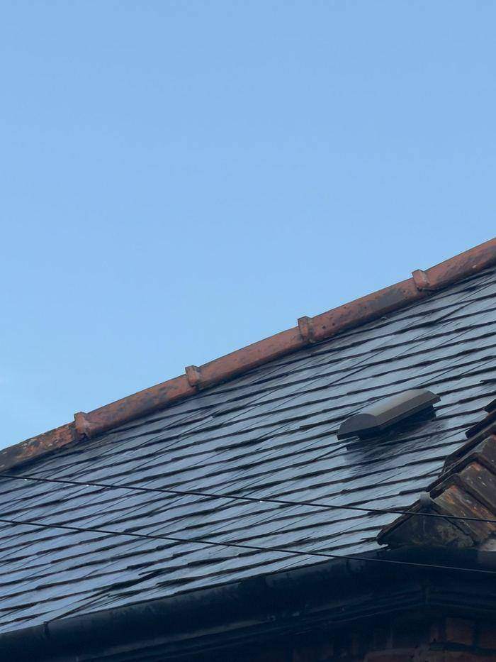Slate roof slope with replacement slates spliced in across the pitch and a slate vent installed near the ridge