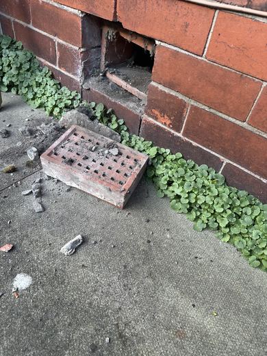 Old clay airbrick removed and set on the ground with the opening cut back square in the brickwork