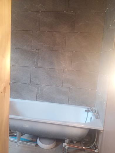 Completed bathroom with new bath, tiling and boxing in