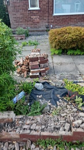 Brick from a demolished garden wall stacked ready to be taken away