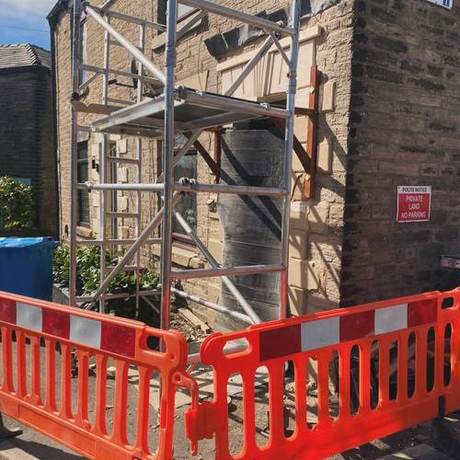 Mobile tower and pedestrian barriers set up at the front door of a stone-built property