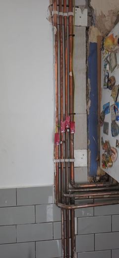 New copper pipework run up the wall behind kitchen units