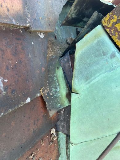 Original copper soakers between the tile courses, oxidised green and split where they have failed at the abutment