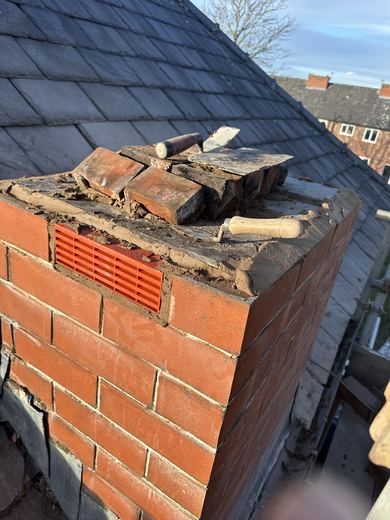 Rebuilt brick chimney stack with the top still open and broken material resting on it
