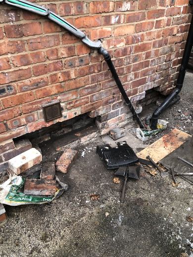Cavity vents cut into the rear elevation brickwork at low level, with the drill and dust extraction to hand