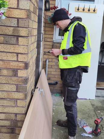 Joiner preparing a new internal door outside a property before hanging it