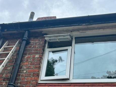 Scaffold at eaves level against a brick elevation with a new downpipe fitted alongside the window