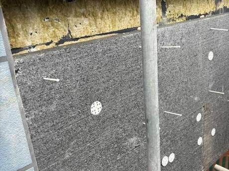 Close view of new breather membrane fixed with washers, with insulation visible above the line of the new work