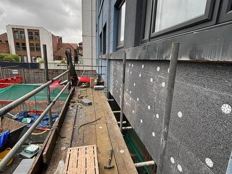 New black breather membrane fixed across an opened-up external wall with insulation washers at regular centres