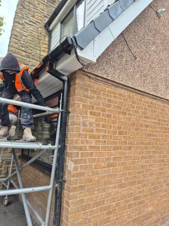 Operative fitting new white fascia and soffit at a gable end from a mobile tower