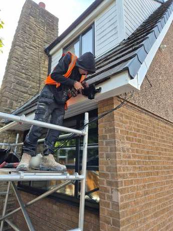 Operative fixing a new white fascia board along the eaves from a mobile tower
