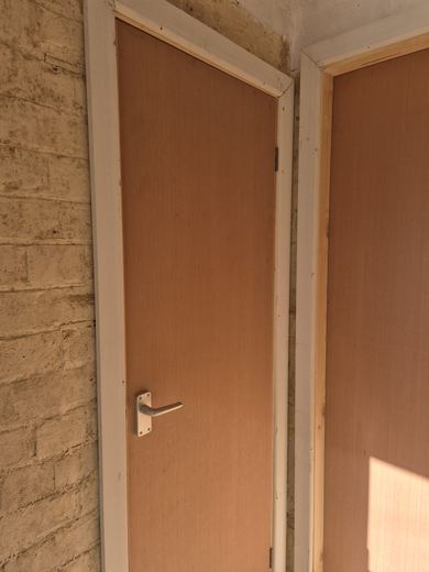New fire door hung in a communal corridor with new lining and ironmongery