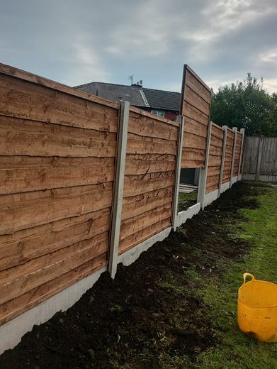 New fence panels and concrete posts run to the end of the garden