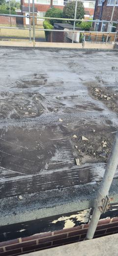 Old flat roof covering, worn and patched, before it is stripped