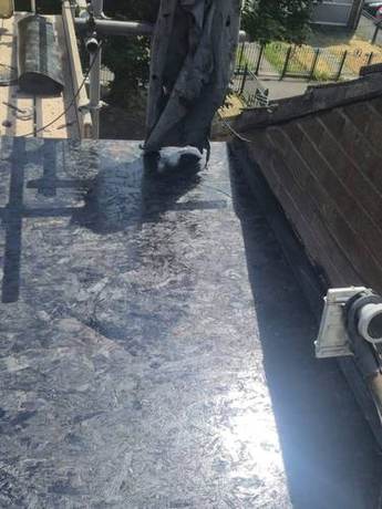 New timber decking laid over a flat roof and primed ready for felting, with the outlet fitted and the parapet alongside