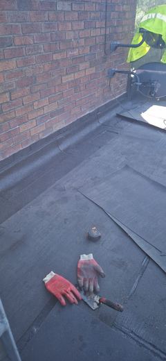 New flat roof covering laid, gloves and tools still on the deck