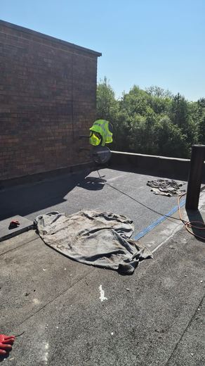 Flat roof part way through re-covering with the operative working across