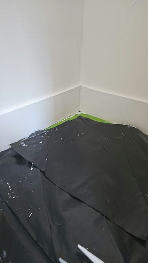 Room corner with the floor fully sheeted and the wall newly finished