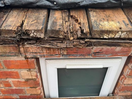 Outrigger roof above a window before renewal, the timber decayed and the covering perished and lifting