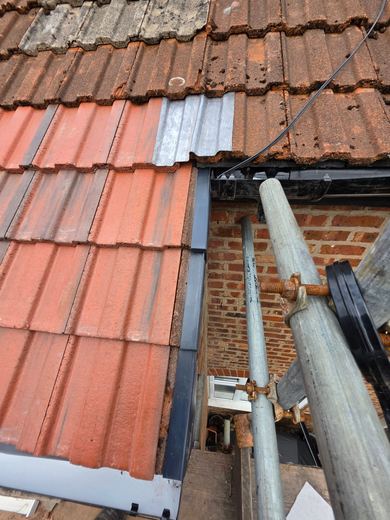 New interlocking tiles being laid on the outrigger and worked up to the existing weathered roof