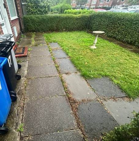 Worn and uneven concrete path running along the rear of a property before renewal
