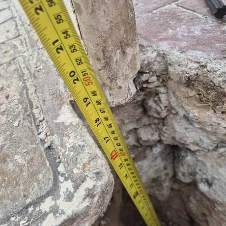 Tape measure run down into a void beneath paving to record its depth before backfilling