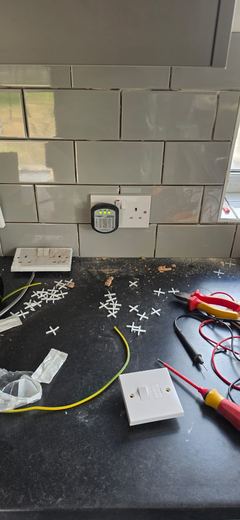Faceplates and test meter laid out on a worktop during second fix