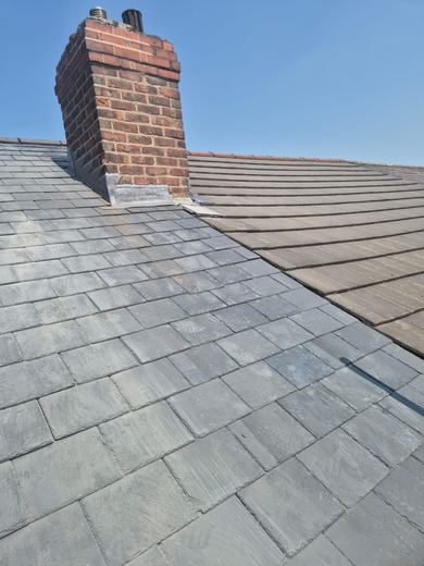 Brick chimney stack rising out of a slate covered roof