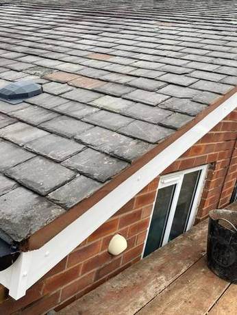 Slate roof slope with a new white fascia and soffit fitted along the eaves below