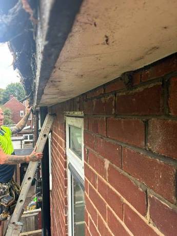 Eaves stripped back with the rafter feet exposed and an operative working from a ladder below