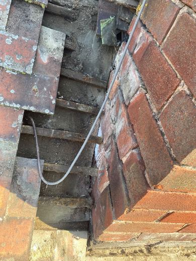Chimney stack opened up with tiles and battens removed to expose the failed flashing and the cable running through