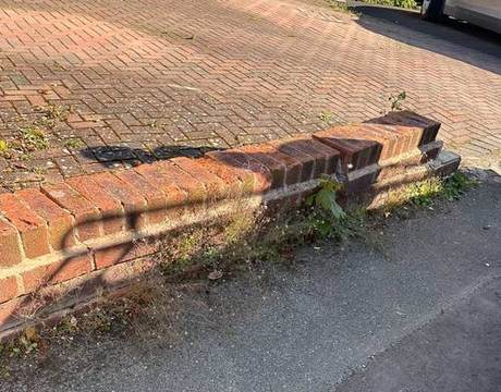 Low front boundary wall that has failed, with brickwork stepped, cracked and pulling away from the footway