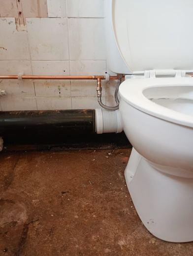 New WC fitted and connected in a stripped bathroom
