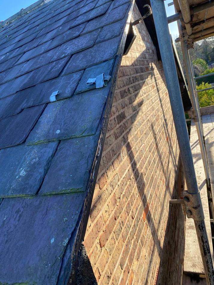 Gable verge with slates lifted and the original timber bargeboard exposed and decayed