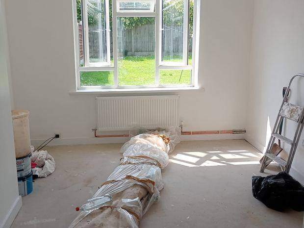 The finished room decorated throughout, with new radiator and pipework and carpet rolled out ready to lay