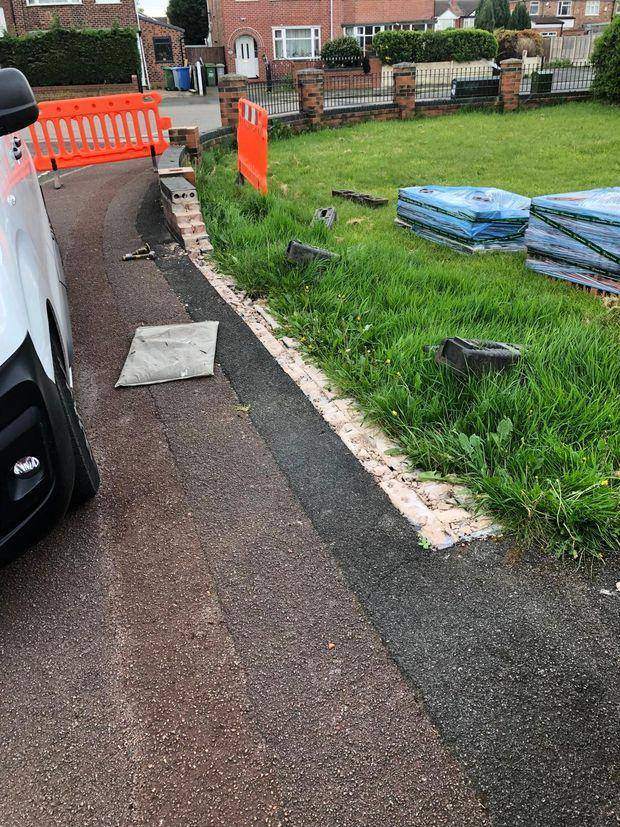 The old boundary wall taken down to footing level, with barriers protecting the footway and new materials stacked on the verge