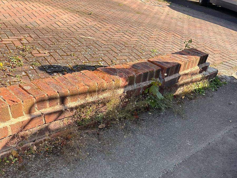 Low front boundary wall that has failed, with brickwork stepped, cracked and pulling away from the footway